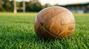 Ballon de rugby marron posé sur herbe verte